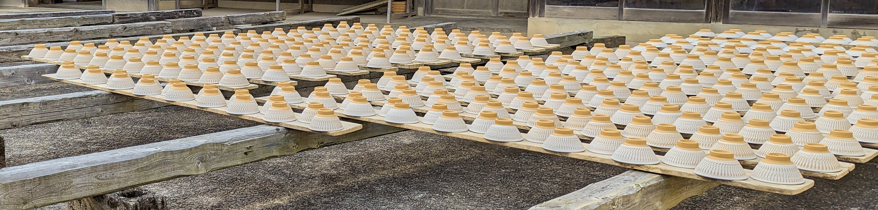 Traditional Japanese building with drying racks of ceramic items outside